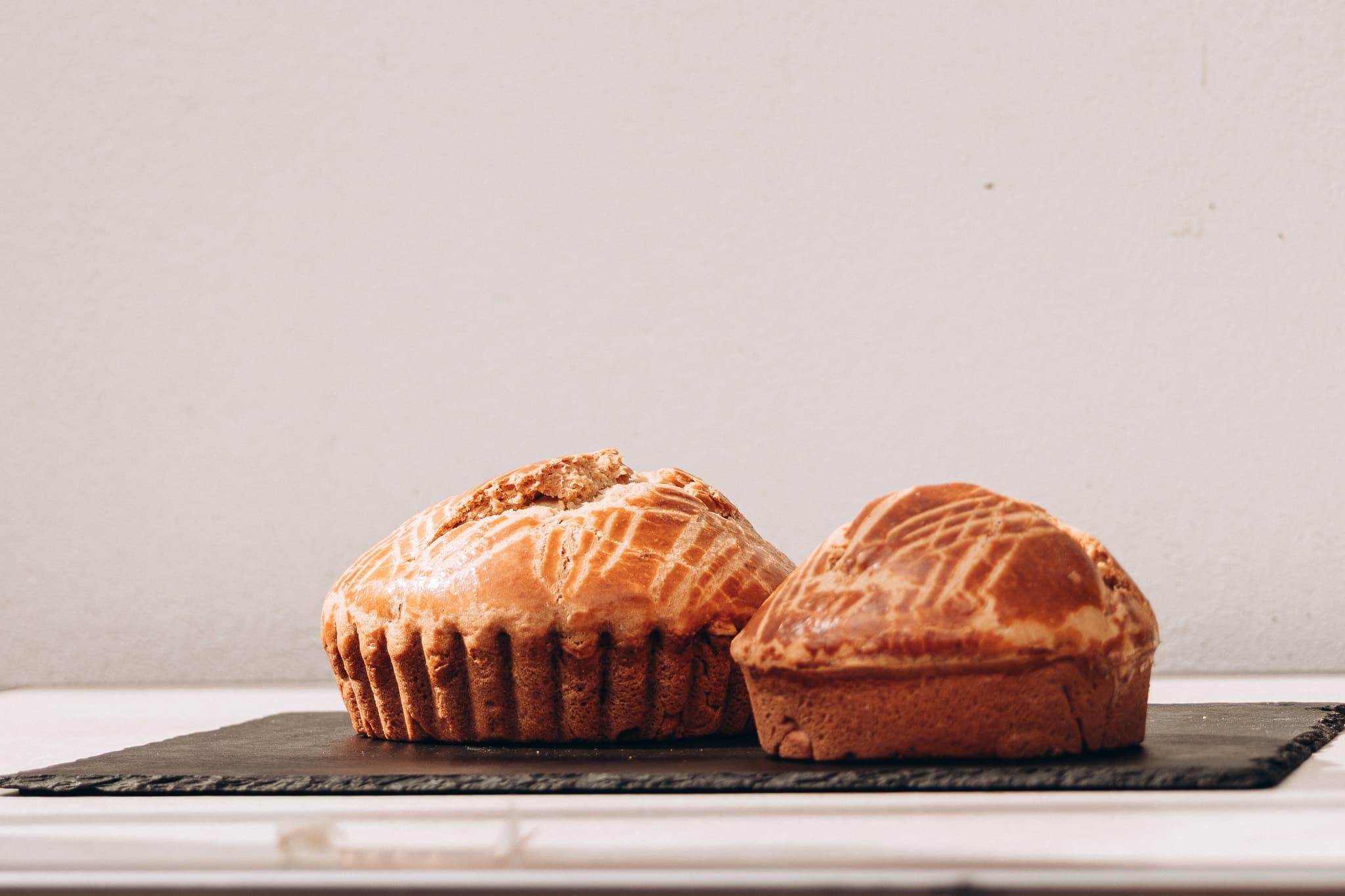 Deux Kouign des Gras dorés côte à côte sur une ardoise